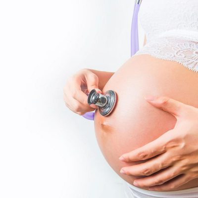 Pregnant Woman Using Stethoscope Examining On Her Baby In Her Be